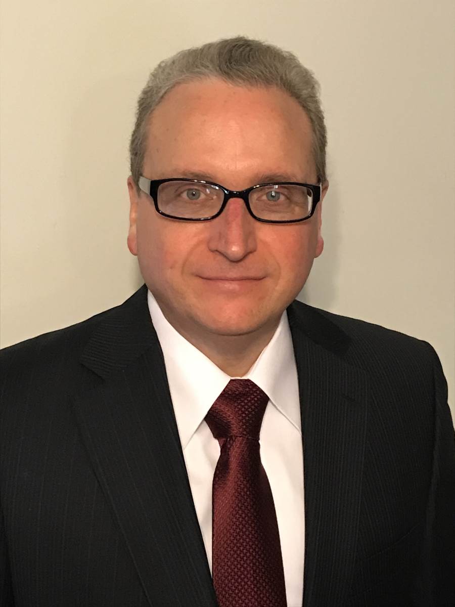 A man smiling at the camera with glasses on